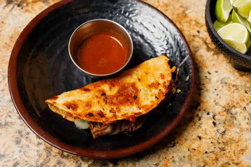 Quesabirria tacos with melted cheese and consommé